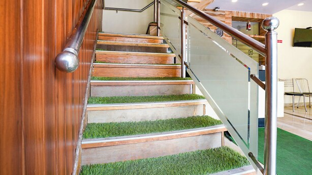 A staircase with wooden steps and a glass railing. - Via Ashir Inn (Mumbai)