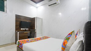 A hotel room with a bed, a TV, a desk, and a wardrobe. - Via Ashir Inn (Mumbai)
