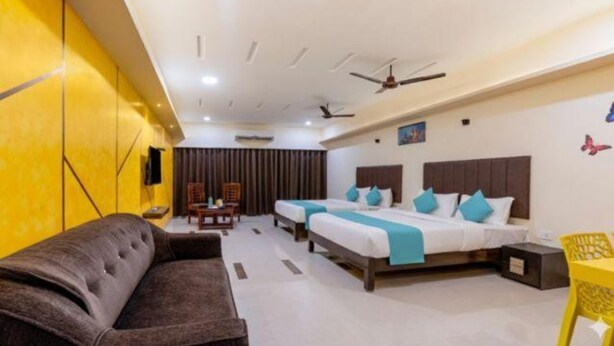 A hotel room with two beds, a sofa, a ceiling fan, and a TV. - Fabhotel D Grand (Madurai)