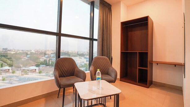 A room with two chairs, a small table, and a bookshelf. - Fabhotel Lotus Inn Pimpri Chinchwad (Pune)