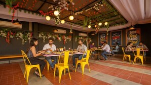 Un restaurant avec des chaises, des tables et des arrangements floraux décoratifs aux murs, le tout dans des tons jaunes.