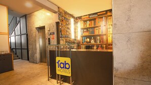 Un espace d’accueil d’hôtel au design moderne, comprenant un comptoir d’accueil, un escalier et une bibliothèque remplie de livres.