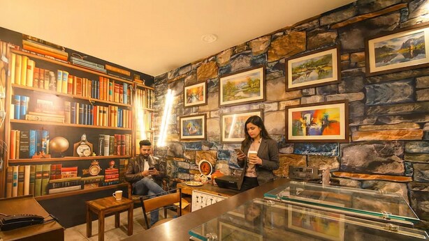 Un coin lecture accueillant, avec des étagères à livres, une table basse et un mur en pierre orné de tableaux.