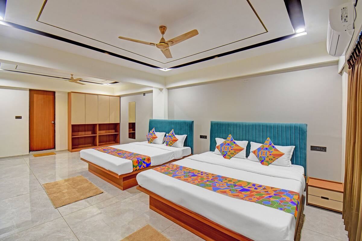A hotel room with two beds, a ceiling fan, a wardrobe, and a bathroom door.
