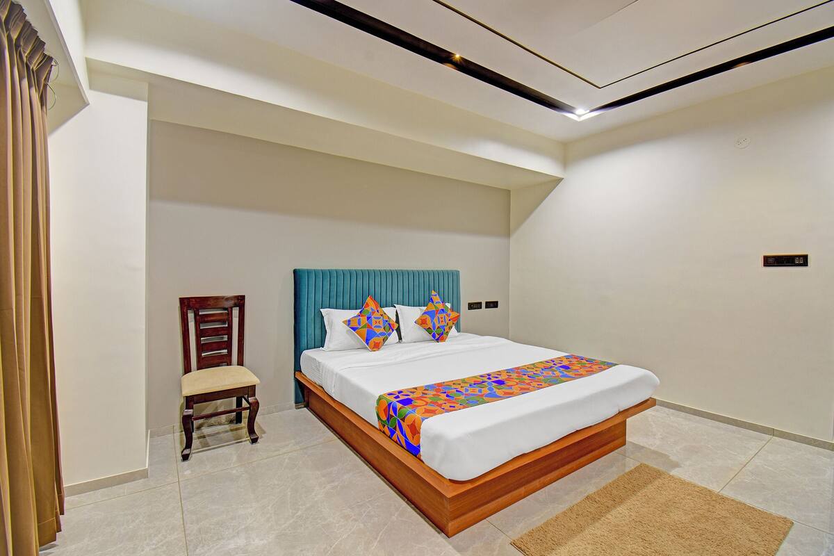 A modern hotel room with a large bed, a wooden chair, and a small desk.