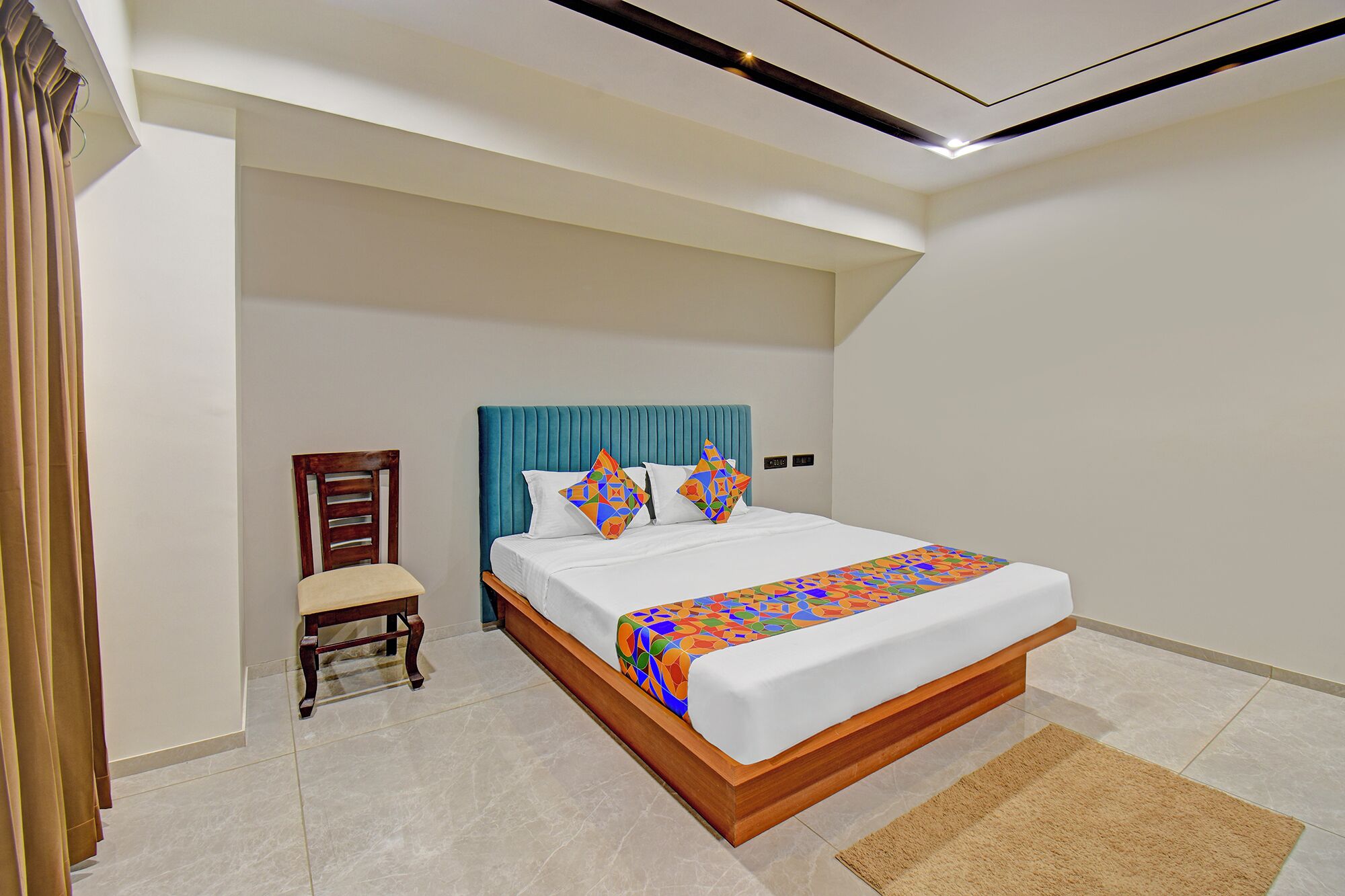 A modern hotel room with a large bed, a wooden chair, and a small desk.