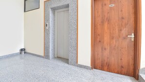 Een gang met een houten deur met de tekst '2de Verdieping' en een metalen deur met een keypad slot.