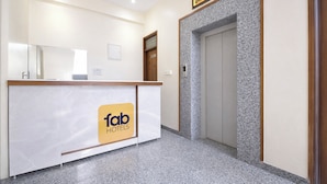 Een hotel receptie met een marmeren balie, een receptieplein en een lift.