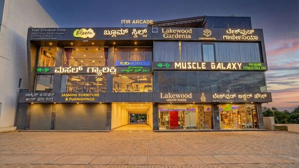 A multi-story building with various businesses including a fitness center, furniture store, and a liquor house. - FabHotel Lakewood Gardenia Bangalore (Anekal)