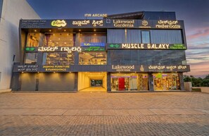 A multi-story building with various businesses including a fitness center, furniture store, and a liquor house. - FabHotel Lakewood Gardenia Bangalore (Anekal)