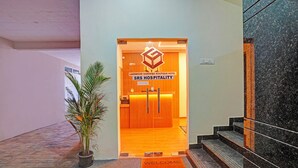 A hotel entrance with a reception desk, a welcome mat, and a potted plant. - FabHotel Lakewood Gardenia Bangalore (Anekal)