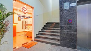 A hotel entrance with a reception desk, a staircase, and a wall-mounted elevator. - FabHotel Lakewood Gardenia Bangalore (Anekal)