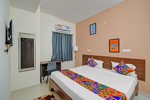 A hotel room with a bed, a desk, a chair, a TV, an air conditioner, and a wall with a picture of an elephant. - FabHotel Aashray - Raheja Mindspace, Madhapur (Hyderabad)