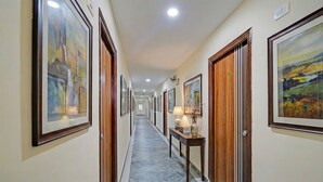 A hallway with framed artwork on the walls, wooden doors, and a marble floor. - Fabhotel Aashray (Hyderabad)
