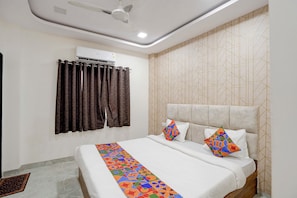 Ein Hotelzimmer mit Bett, Deckenventilator, Klimaanlage und einer Wand mit Muster.
