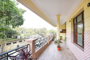 A balcony with a view of a parking area and buildings, a potted plant, and a tiled wall. - Fabhotel Surya Palace 1 (Chandigarh)