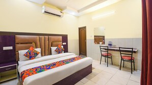 Quarto de hotel com uma cama, uma escrivaninha e uma cadeira.