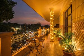 Ein Balkon mit Sitzgelegenheit, Blick auf die Stadt und dekorativer Beleuchtung.