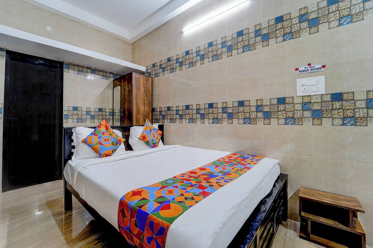 A hotel room with a bed, a wooden wardrobe, a tiled wall, and a small wooden nightstand.