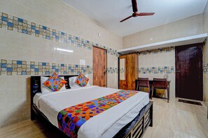 A bedroom with a bed, a ceiling fan, a wooden wardrobe, and a door. - Via KRV Residency (Coimbatore)