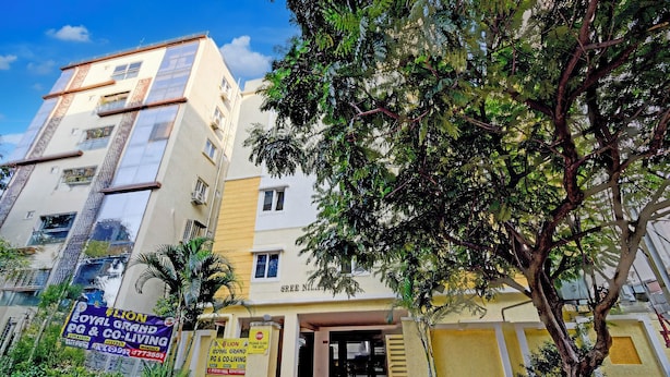 A multi-story building with a yellow and white facade, a gated entrance, and a large tree in front. - Fabhotel Rk Grand (Hyderabad)