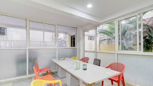A conference room with a white table and colorful chairs, large windows with views of palm trees, and a tiled floor. - Fabhotel Rk Grand (Hyderabad)
