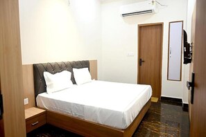 Une chambre à coucher comprenant un lit, une table de chevet, une armoire et un appareil de climatisation.