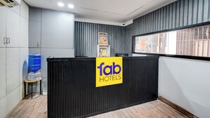 Een hotel receptie met een zwart aanrecht, een waterdispenser en een bordje met de tekst 'Tab Hotels'.