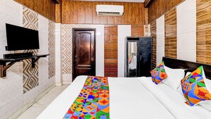 A hotel room with a large bed, a TV, and a refrigerator. - Fabhotel Csrx (Ghaziabad)