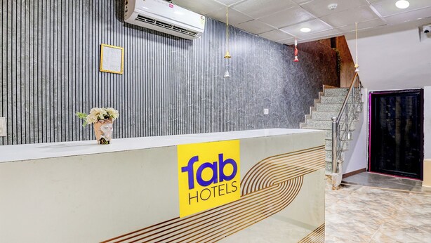 A reception desk with a 'fab hotels' sign, a staircase, and an air conditioning unit. - Fabhotel Csrx (Ghaziabad)
