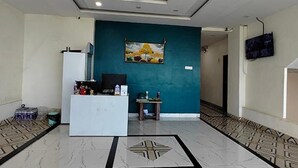 Zona de recepció amb una paret d'accent color aquatint, un quadre, mostrador de recepci ó, televisió i paviment amb dibuixos.