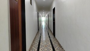 Un passadís llarg i estret amb un sòl de disseny, portes a banda i banda, i un sostre amb il·luminació empotrada.