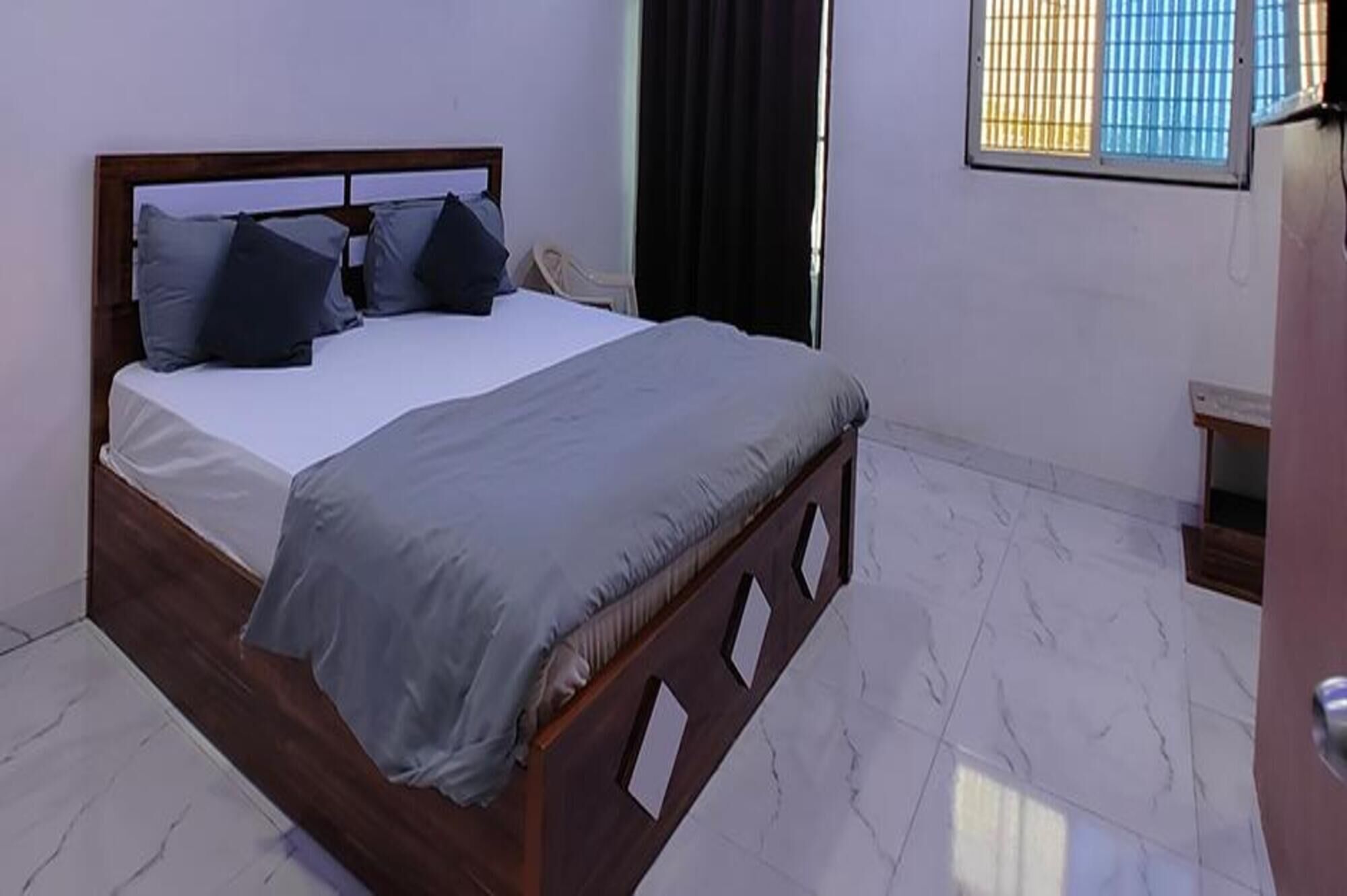 A bedroom with a bed, a window with blinds, and a door.