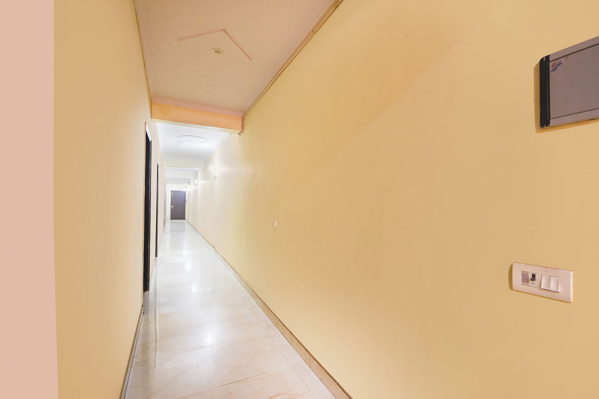 A long, narrow hallway with a light-colored floor and walls, leading to a door at the end.