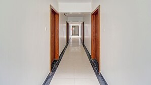 A long, narrow hallway with wooden doors on either side and a tiled floor. - Fabhotel Panchsheel Crown (Pune)