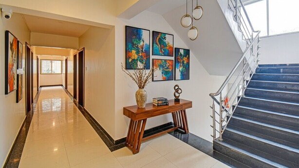 A modern hotel lobby with a long hallway, a staircase, and artwork on the walls. - Fabhotel Panchsheel Crown (Pune)