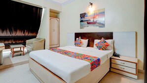 Une chambre d’hôtel avec un grand lit, un bureau, une chaise et une armoire.