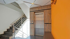 Un ascenseur moderne aux finitions métalliques, un escalier avec une rampe en métal et un sol en pierre polie.