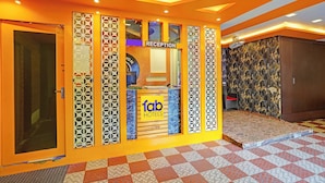 Un espace d’accueil avec une enseigne indiquant « Réception », une autre indiquant « Fab Hotels » et un mur décoré de motifs.