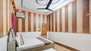 Une pièce avec un lit, un ventilateur de plafond et une porte.