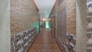 Un couloir aux murs ornés de motifs et au sol carrelé, qui mène à un escalier.