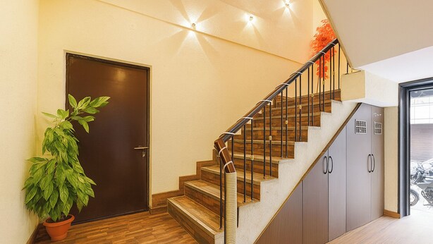 A staircase with wooden steps and metal railings, leading to a door with a potted plant beside it. - Fabhotel Z Heart (New Delhi)