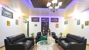 A reception area with two black leather sofas, a glass coffee table, and framed artwork on the walls. - Fabhotel Z Heart (New Delhi)