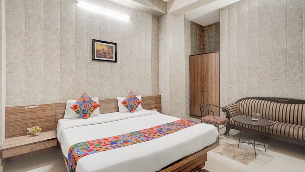 Une chambre d’hôtel moderne avec un grand lit, un canapé, une petite table et une armoire.