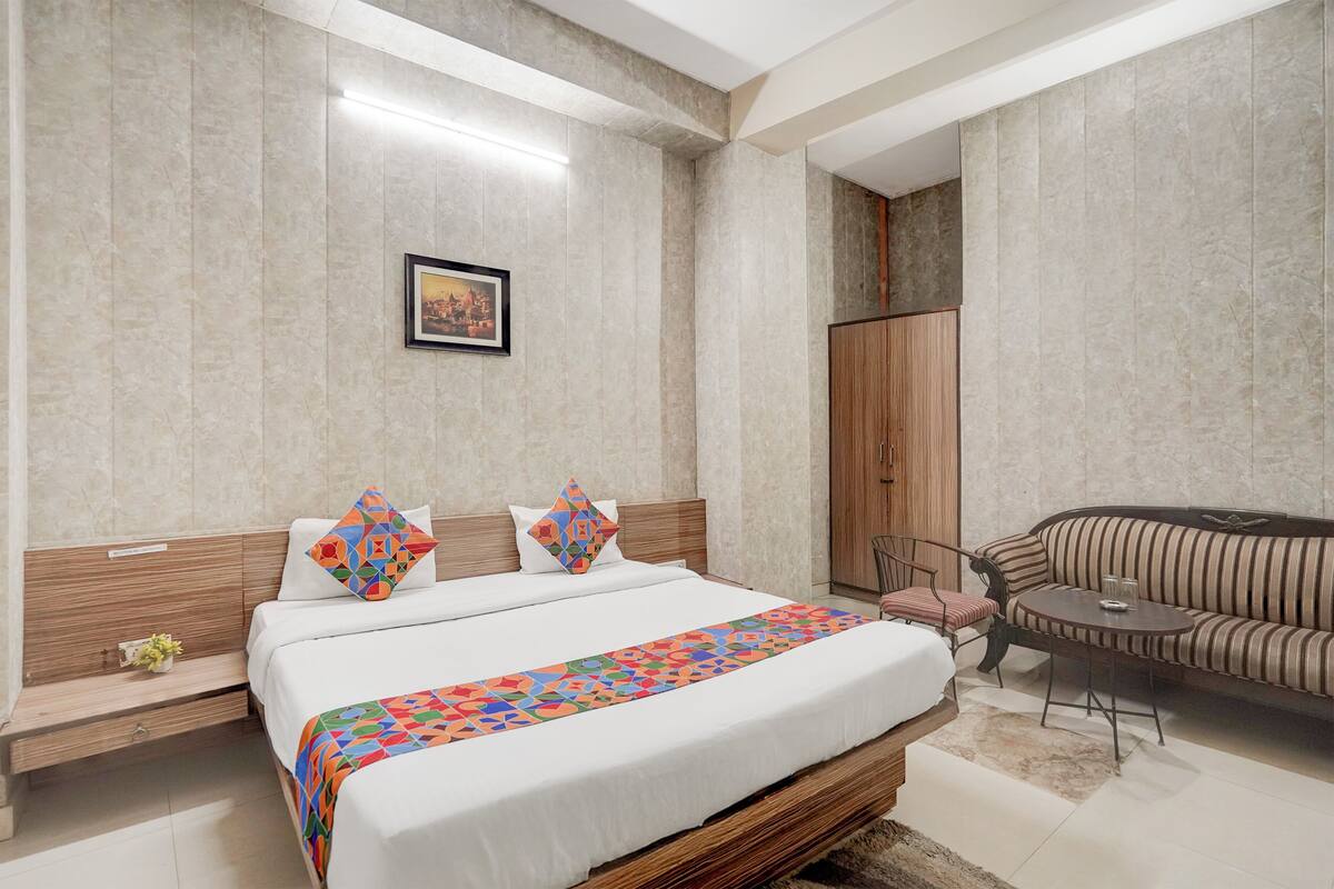 Una habitación de hotel moderna con una cama grande, un sofá, una mesita y un armario.