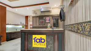 Un espace d'accueil avec une enseigne indiquant « fab hotels », un comptoir de réception, un téléphone fixé au mur et des tableaux encadrés.