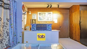 A reception desk with a 'fab hotels' sign, a framed welcome sign, and a wooden wall with vertical slats. - Fabhotel Stay Inn I (Noida)