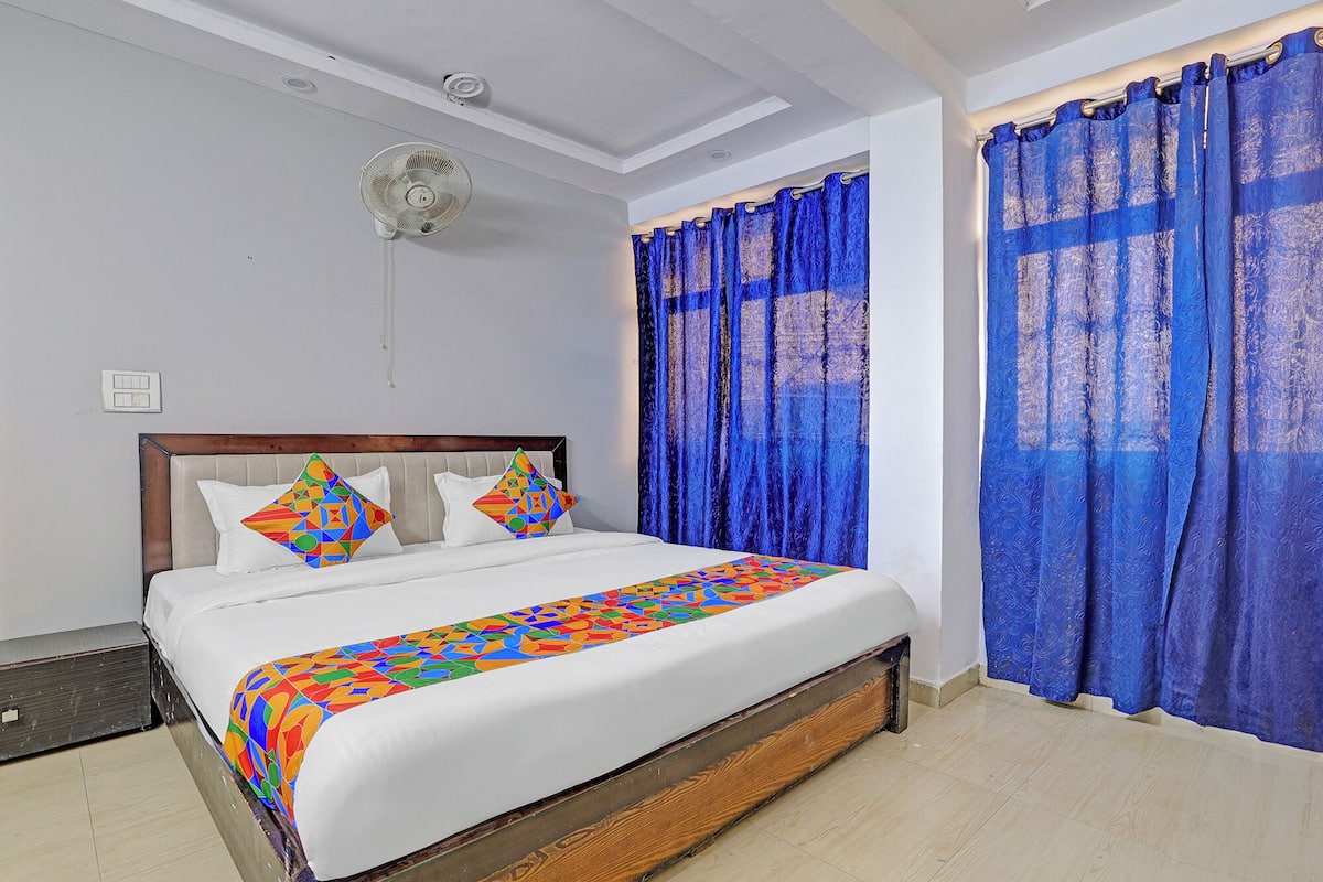 A bedroom with a bed, a ceiling fan, and blue curtains.
