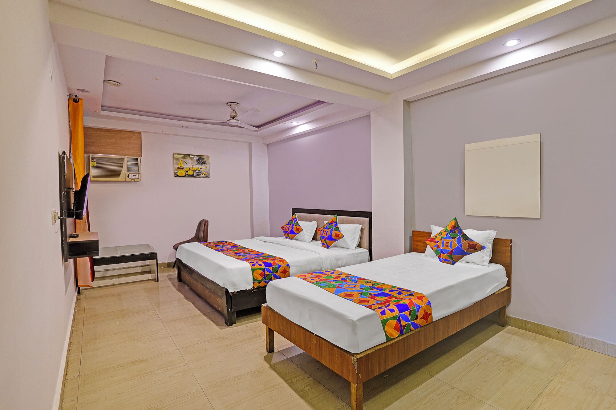 A hotel room with two wooden beds, a ceiling fan, and a painting on the wall.