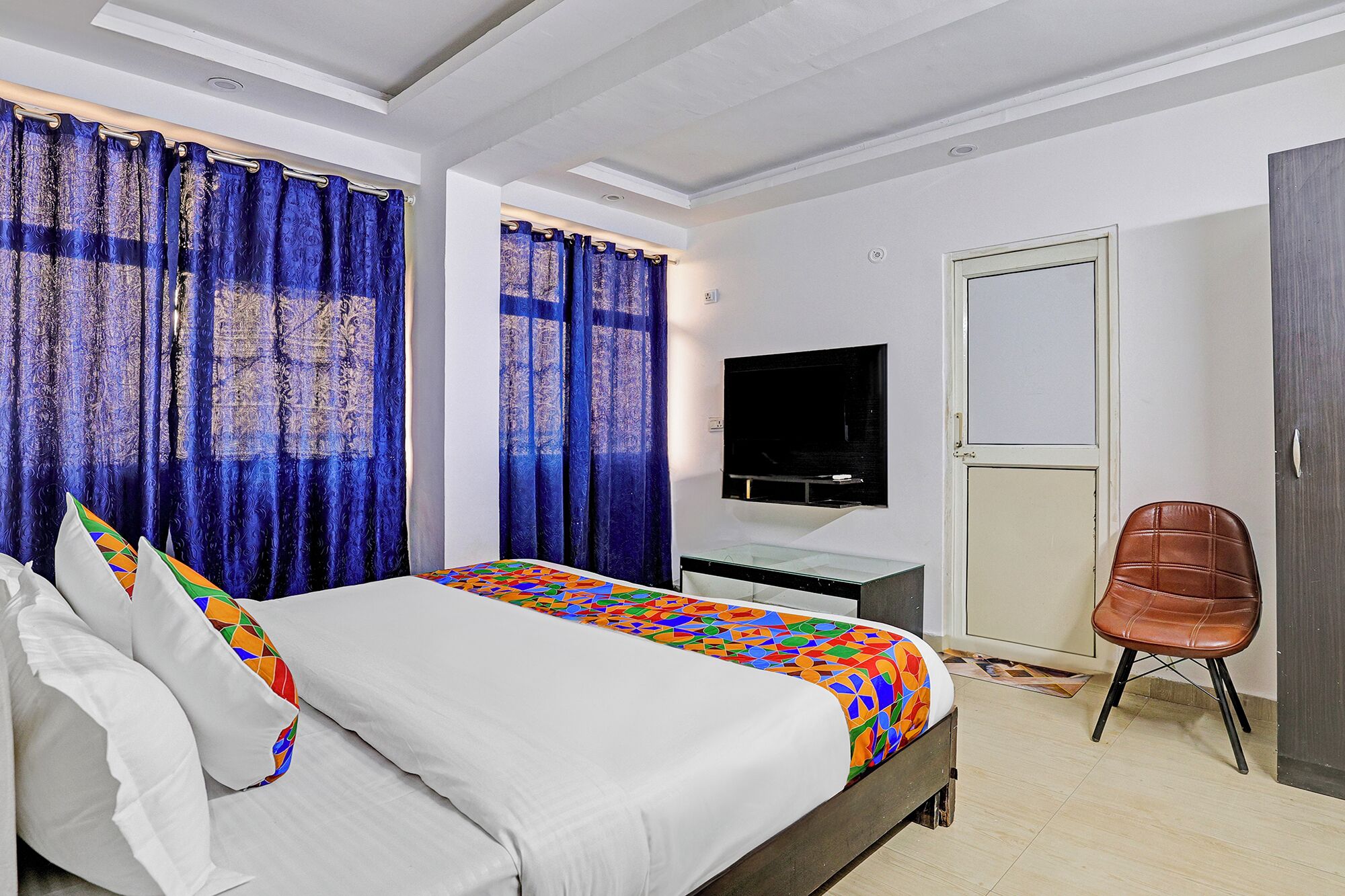 Una habitación de hotel con cama, televisor, escritorio y silla.